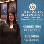 Graduate posing next to BCOIS banner